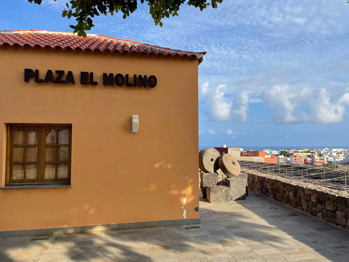 Ein altes Mühlenhaus steht auf einer Anhöhe mit Blick auf das Meer. Auf dem Platz vor dem Haus stehen zwei Mahlsteine.